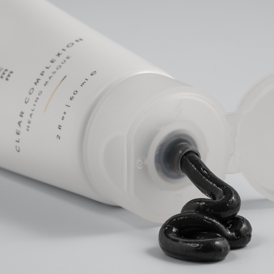 White tube with Green Envee black charcoal healing gel being squeezed out on a light gray background