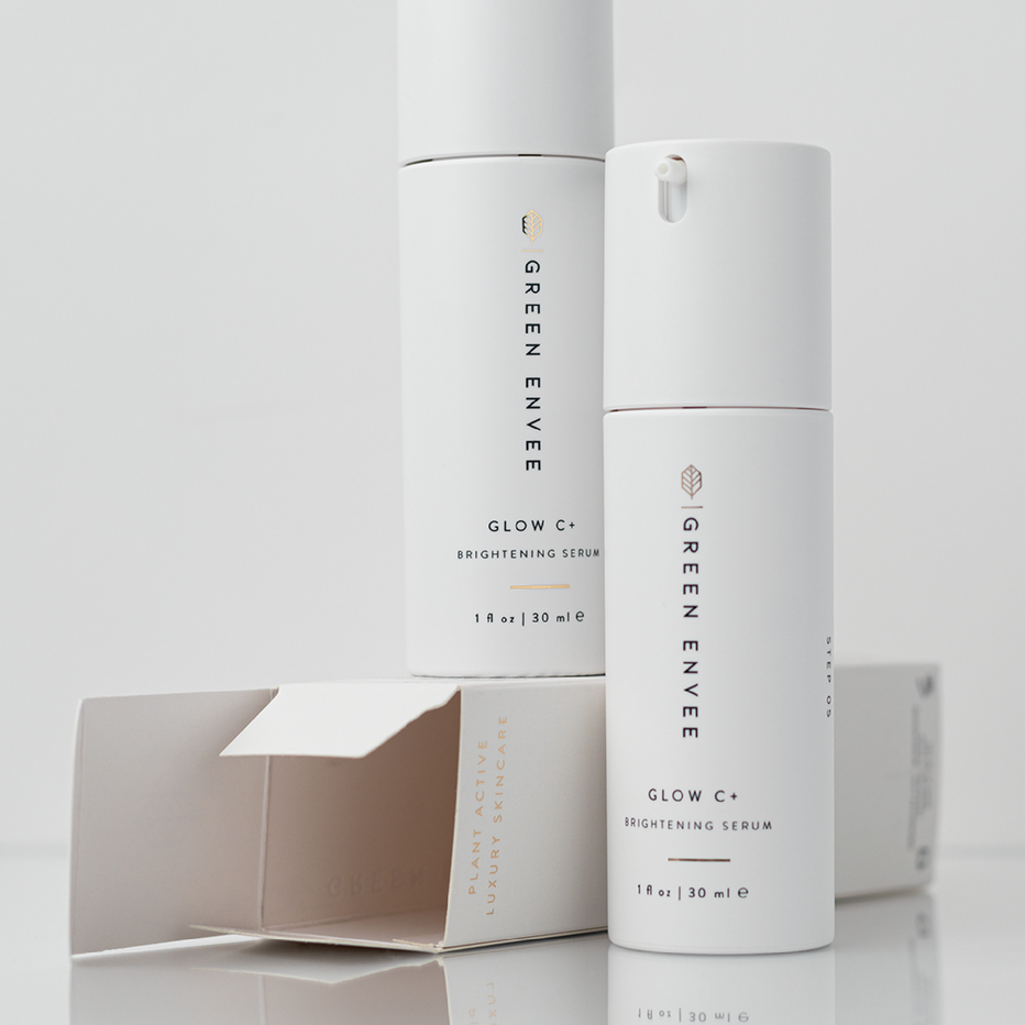 Green Envee Glow C+ brightening serum bottle and packaging on a light gray background