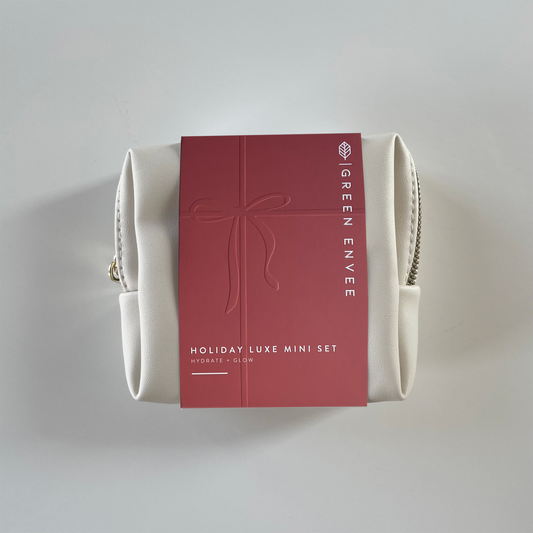 White holiday cosmetic bag with a red label featuring 'Green Envee Holiday Luxe Mini Set' on a light gray background
